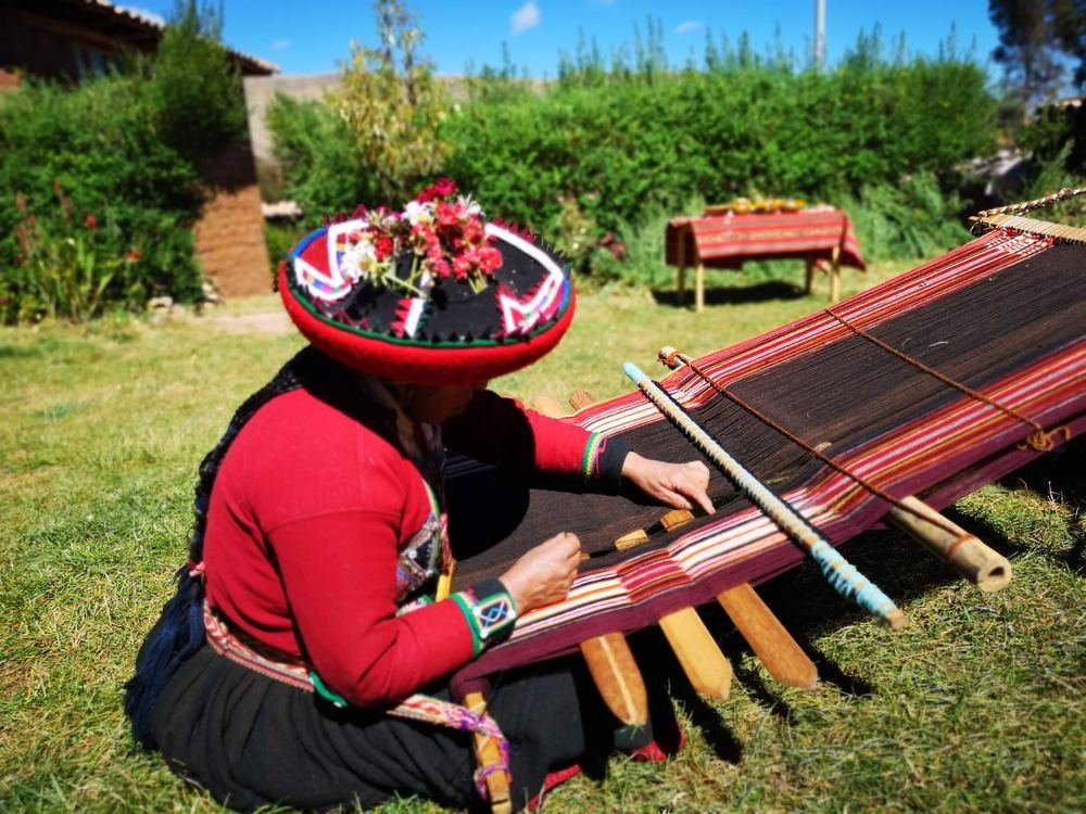 Andean woman weaving on a traditional backstrap loom in Chinchero
